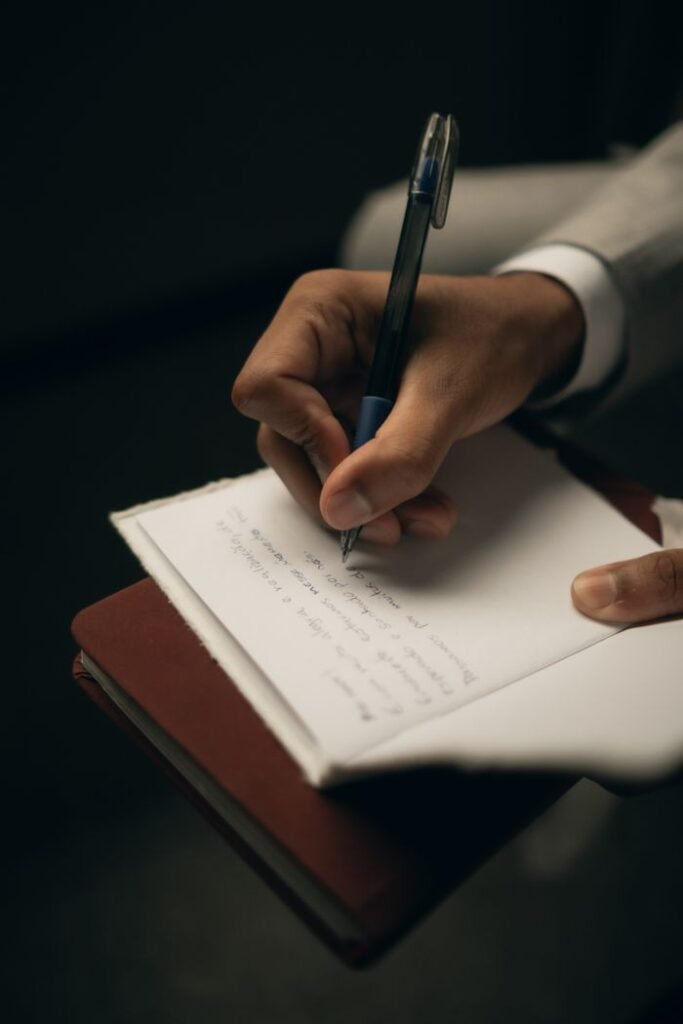 Handwriting in a notebook with a pen, showing creativity and focus.