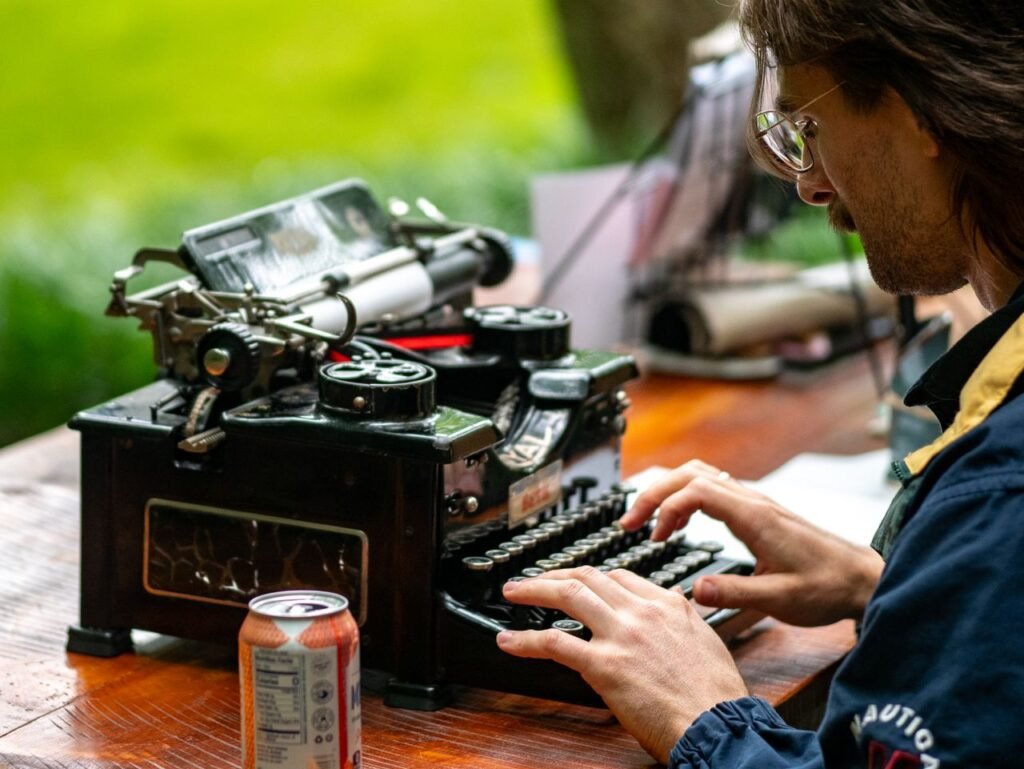 A focused individual typing on a vintage typewriter outdoors, capturing a retro writing scene.