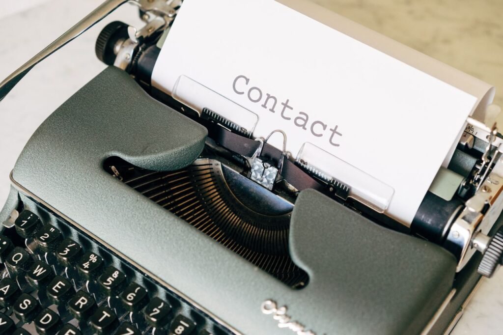 Close-up of a vintage typewriter typing the word 'Contact' on paper, evoking nostalgia.
